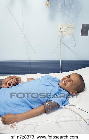 African boy laying in hospital bed wincing View Large Photo Image Stock Image - African boy laying in hospital bed wincing. Fotosearch