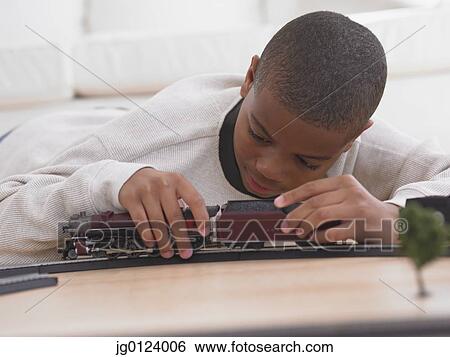 Stock Photograph - African boy playing with model train on floor. Fotosearch
