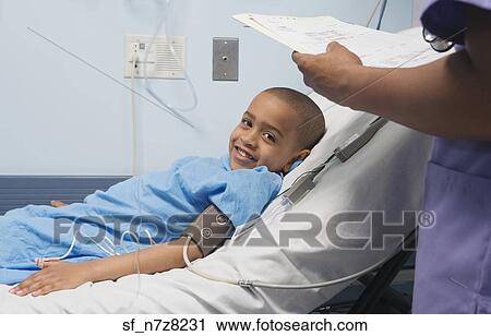 Stock Image - African boy smiling in hospital bed. Fotosearch