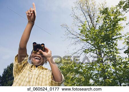 African boy using binoculars and pointing in park View Large Photo Image Stock Photo - African boy using binoculars and pointing in park. Fotosearch