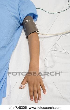 Stock Photograph - African child’s arm with blood pressure cuff in hospital bed. Fotosearch
