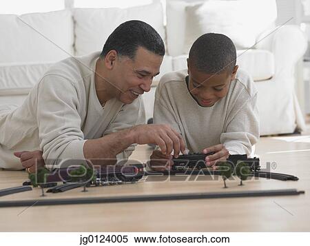 African father and son playing with model train on floor View Large Photo Image Stock Photography - African father and son playing with model train on floor. Fotosearch