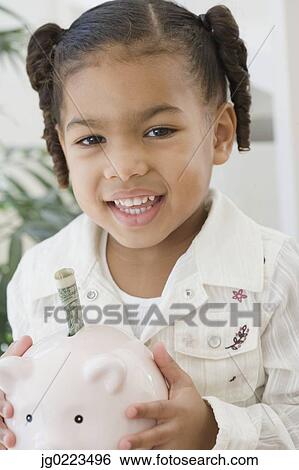 Stock Photograph - African girl holding piggy bank. Fotosearch