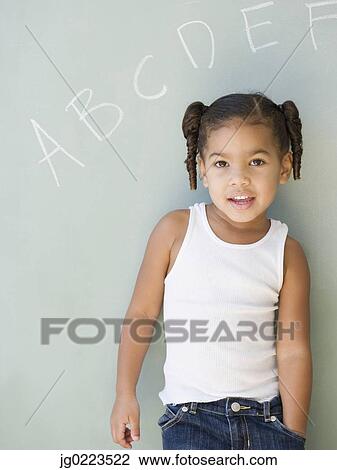 Stock Image - African girl leaning against blackboard. Fotosearch