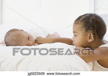 African girl looking at baby sibling View Large Photo Image Stock Photo - African girl looking at baby sibling. Fotosearch