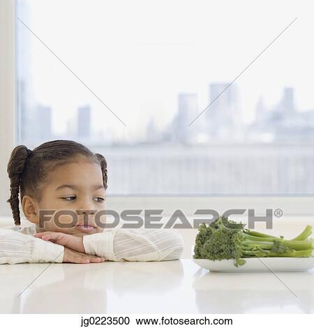 African girl looking at broccoli on table View Large Photo Image Stock Image - African girl looking at broccoli on table. Fotosearch