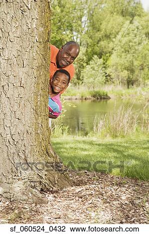 African grandfather and grandson peeking out from behind tree in park View Large Photo Image Stock Image - African grandfather and grandson peeking out from behind tree in park. Fotosearch