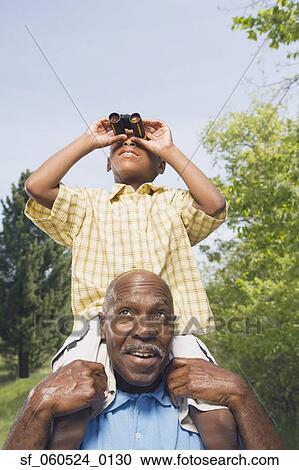 African grandfather carrying grandson on shoulders using binoculars in park View Large Photo Image Stock Image - African grandfather carrying grandson on shoulders using binoculars in park. Fotosearch