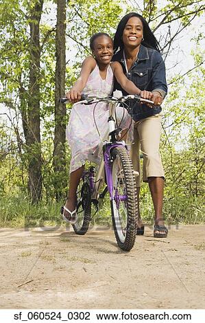 African mother teaching daughter to ride a bicycle in park View Large Photo Image Stock Image - African mother teaching daughter to ride a bicycle in park. Fotosearch