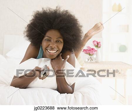 African woman changing channel with remote control View Large Photo Image Stock Photo - African woman changing channel with remote control. Fotosearch