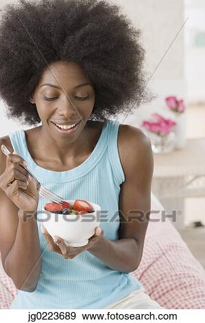 African woman eating bowl of fruit View Large Photo Image Stock Photo - African woman eating bowl of fruit. Fotosearch