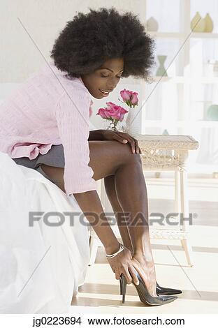 Picture - African woman putting on high heels. Fotosearch