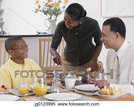 Stock Photography - African woman serving breakfast to husband and son. Fotosearch