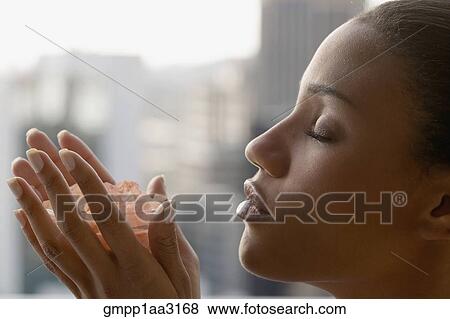 Stock Photo - African woman with eyes closed holding bowl of crystals. Fotosearch