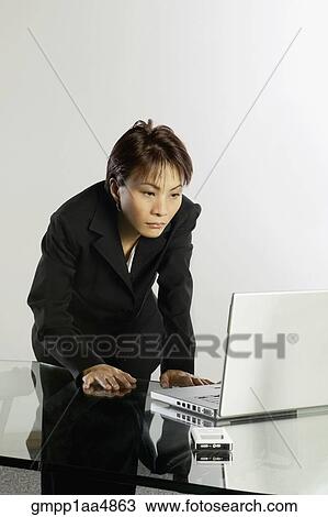 Stock Image - Asian businesswoman looking at laptop. Fotosearch