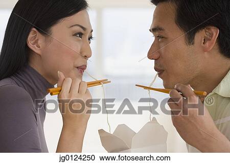 Asian couple eating noodles with chopsticks View Large Photo Image Stock Image - Asian couple eating noodles with chopsticks. Fotosearch