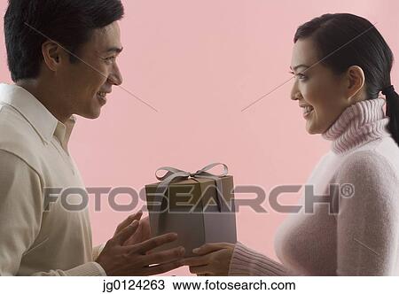 Stock Image - Asian couple exchanging gifts. Fotosearch