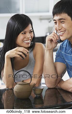 Asian couple having tea and using cell phone View Large Photo Image Stock Photo - Asian couple having tea and using cell phone. Fotosearch