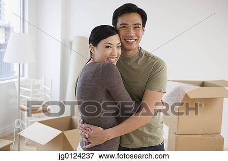 Stock Photo - Asian couple hugging in new house. Fotosearch