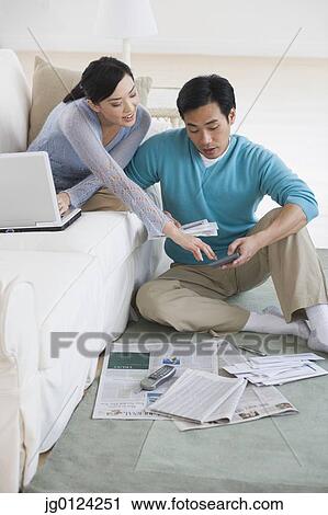 Stock Image - Asian couple sitting in living room. Fotosearch