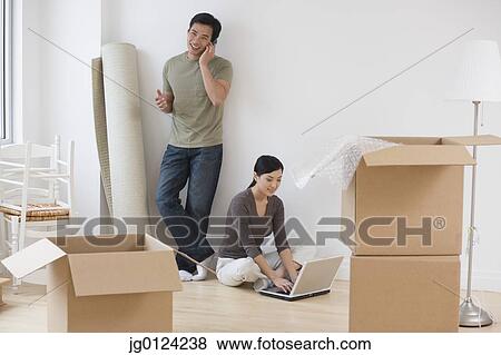 Stock Photo - Asian couple taking break from moving. Fotosearch
