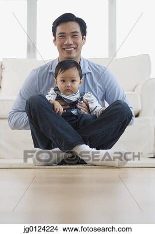 Picture - Asian father sitting on floor with baby. Fotosearch