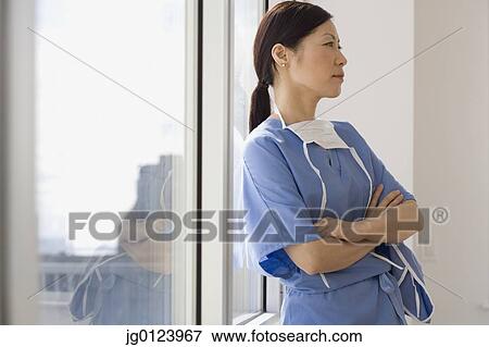 Asian female doctor leaning against window with arms crossed View Large Photo Image Stock Photo - Asian female doctor leaning against window with arms crossed. Fotosearch