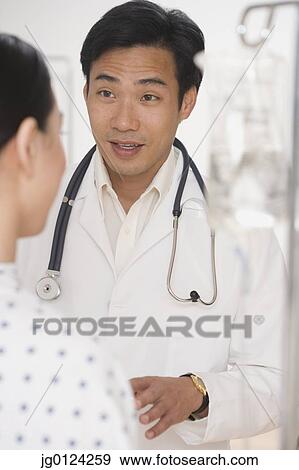 Asian male doctor talking to patient View Large Photo Image Stock Photo - Asian male doctor talking to patient. Fotosearch