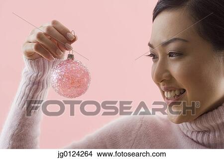 Picture - Asian woman holding Christmas ornament. Fotosearch