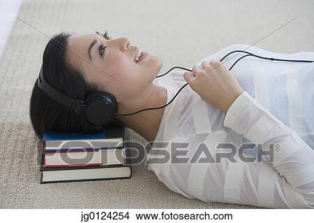 Asian woman listening to headphones on floor View Large Photo Image Picture - Asian woman listening to headphones on floor. Fotosearch