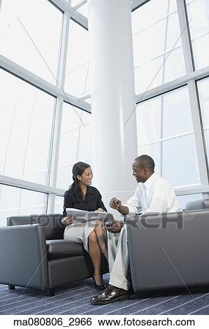 Businessman and businesswoman talking in office lobby View Large Photo Image Stock Photograph - Businessman and businesswoman talking in office lobby. Fotosearch