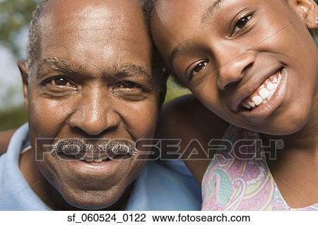 Stock Image - Close up of African grandfather and granddaughter smiling. Fotosearch