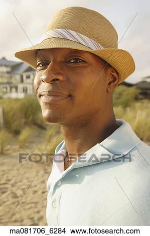 Picture - Close up of African man in hat at beach. Fotosearch