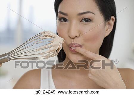 Close up of Asian woman tasting batter on whisk View Large Photo Image Stock Photo - Close up of Asian woman tasting batter on whisk. Fotosearch