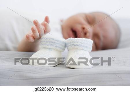 Close up of baby booties next to sleeping newborn baby View Large Photo Image Stock Image - Close up of baby booties next to sleeping newborn baby. Fotosearch