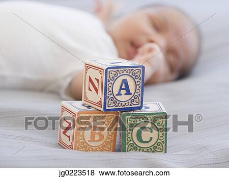Stock Photo - Close up of blocks next to newborn sleeping baby. Fotosearch