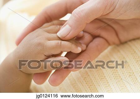 Stock Photograph - Close up of Hispanic mother and baby holding hands. Fotosearch