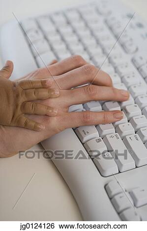 Stock Photograph - Close up of Hispanic mother’s and baby’s hands on computer keyboard. Fotosearch