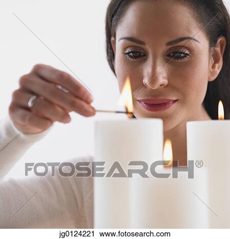 Stock Image - Close up of Hispanic woman lighting candles. Fotosearch