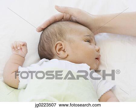 Stock Photo - Close up of mother touching newborn baby's head. Fotosearch