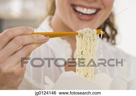 Close up of woman eating noodles with chopsticks View Large Photo Image Stock Photograph - Close up of woman eating noodles with chopsticks. Fotosearch