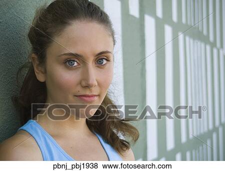 Close up of young woman leaning against wall View Large Photo Image Stock Photo - Close up of young woman leaning against wall. Fotosearch