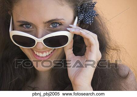 Stock Photography - Close up of young woman smiling over top of sunglasses. Fotosearch