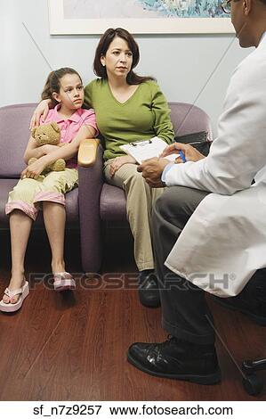Doctor talking to Hispanic mother and daughter in waiting room View Large Photo Image Stock Photo - Doctor talking to Hispanic mother and daughter in waiting room. Fotosearch