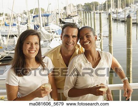 Stock Photo - Friends smiling on marina balcony. Fotosearch