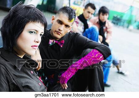 Stock Image - Group of punk Hispanic teenagers sitting on urban sidewalk. Fotosearch