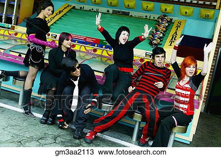 Stock Image - Group of punk Hispanic teenagers cheering in carnival booth. Fotosearch