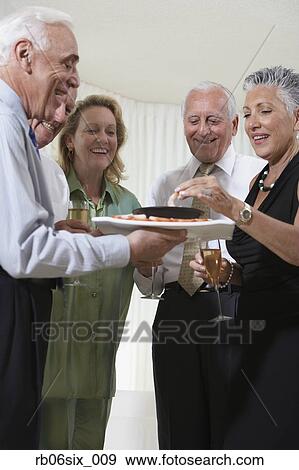 Stock Photo - Group of seniors at party eating hors d’oeuvres. Fotosearch