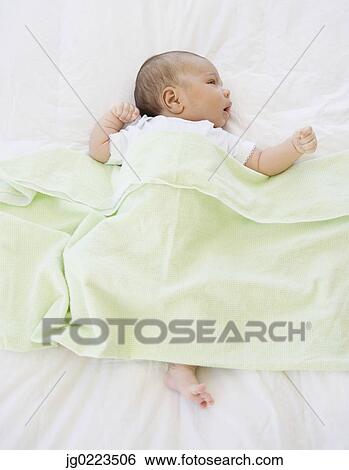 Stock Photograph - High angle view of newborn baby under blanket. Fotosearch