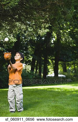 Stock Photograph - Hispanic boy playing with baseball in park. Fotosearch